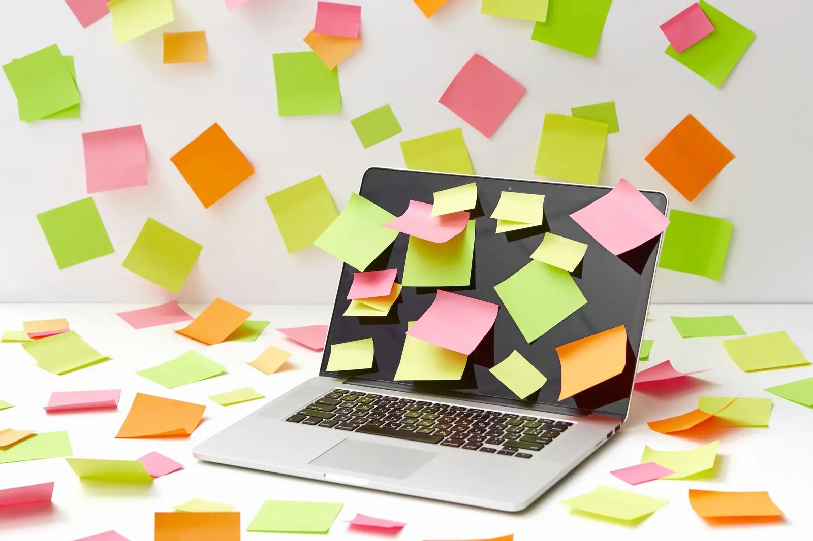 A laptop buried under dozens of sticky notes