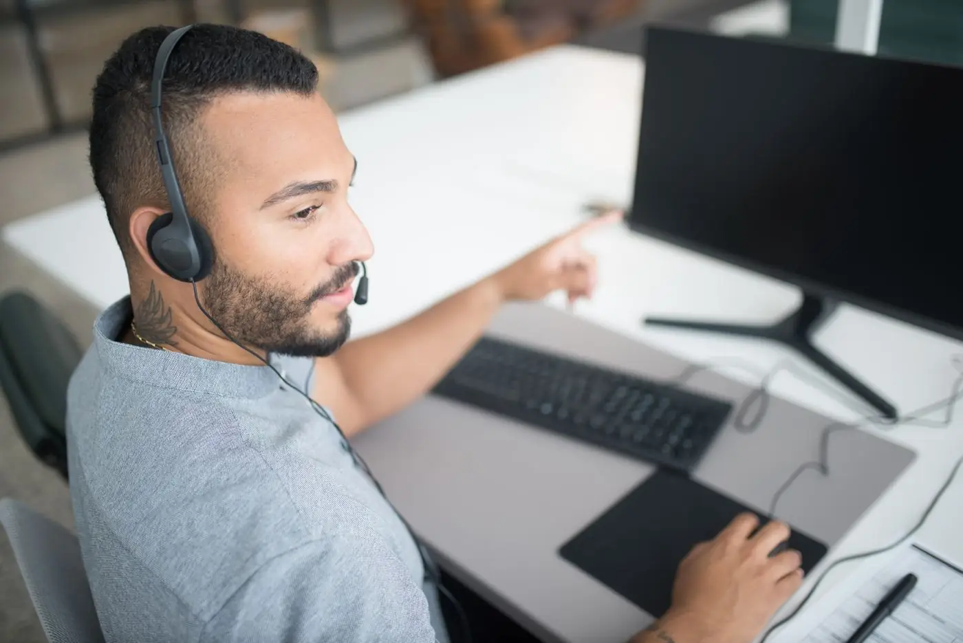 A support agent wearing a headset, working at a computer